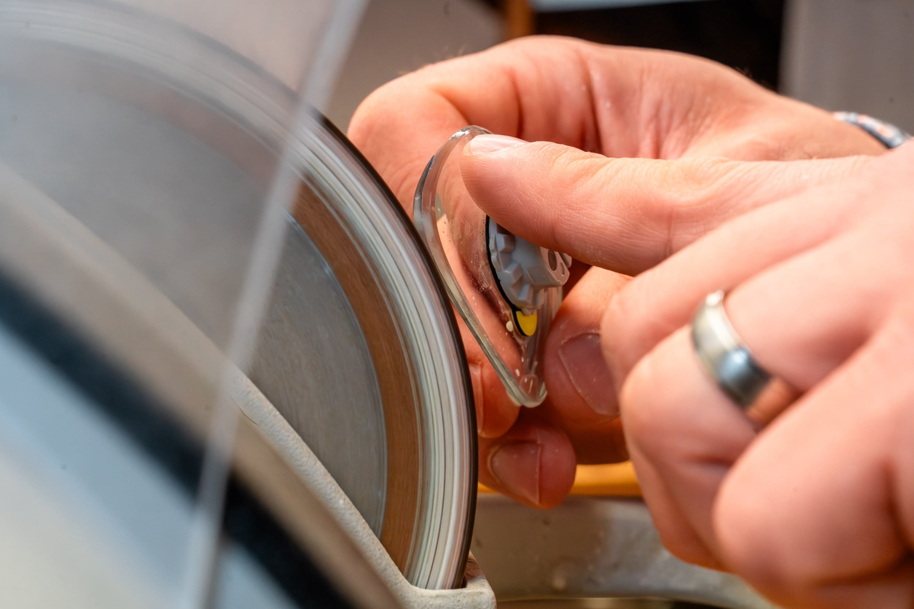 Brillenglas wird auf der Schleifmaschine in Form gebracht